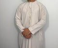 A man wearing a beige Classic Emirati Thobe with a chest zip opening and Omani tassel.