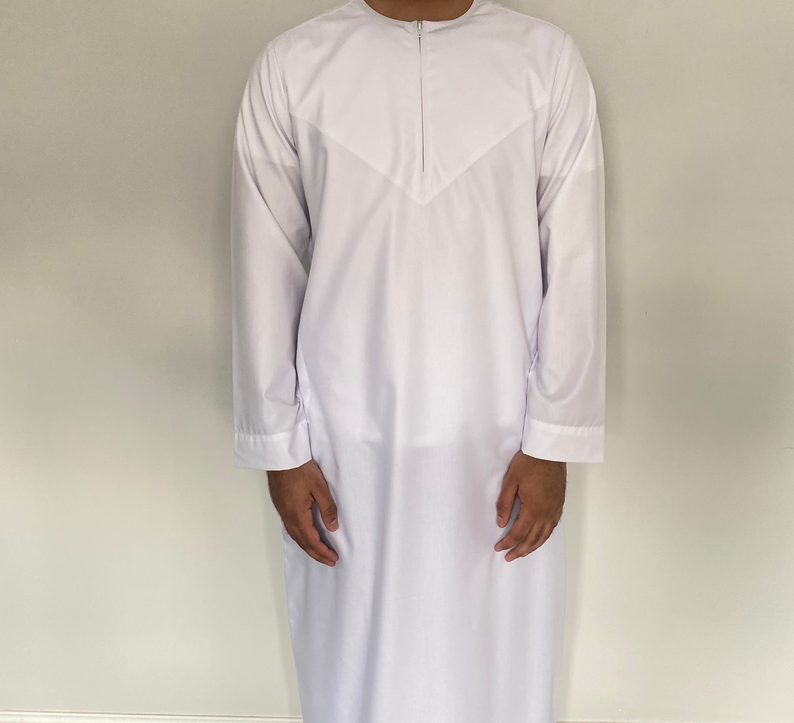 A man wearing a white traditional Omani style thobe with a half zip.