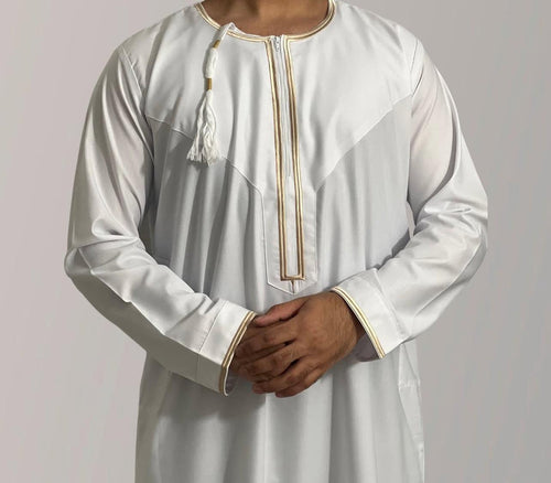 A child wearing a white and gold Omani thobe with decorative details.