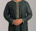 A child wearing a green and gold Omani thobe with detailed trim.