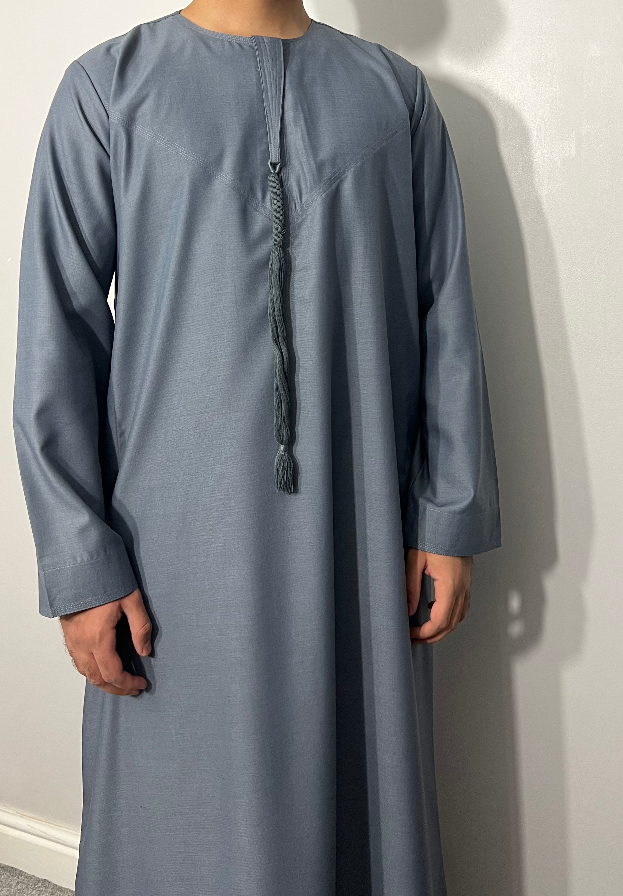 A child wearing a grey Omani style thobe with a half zip.