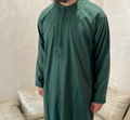 man wearing a green traditional moroccan thobe with intricate detailing on a neutral background